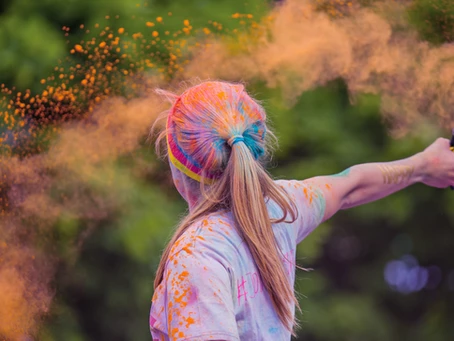 girl with long blonde hair tied up throwing colour powder around